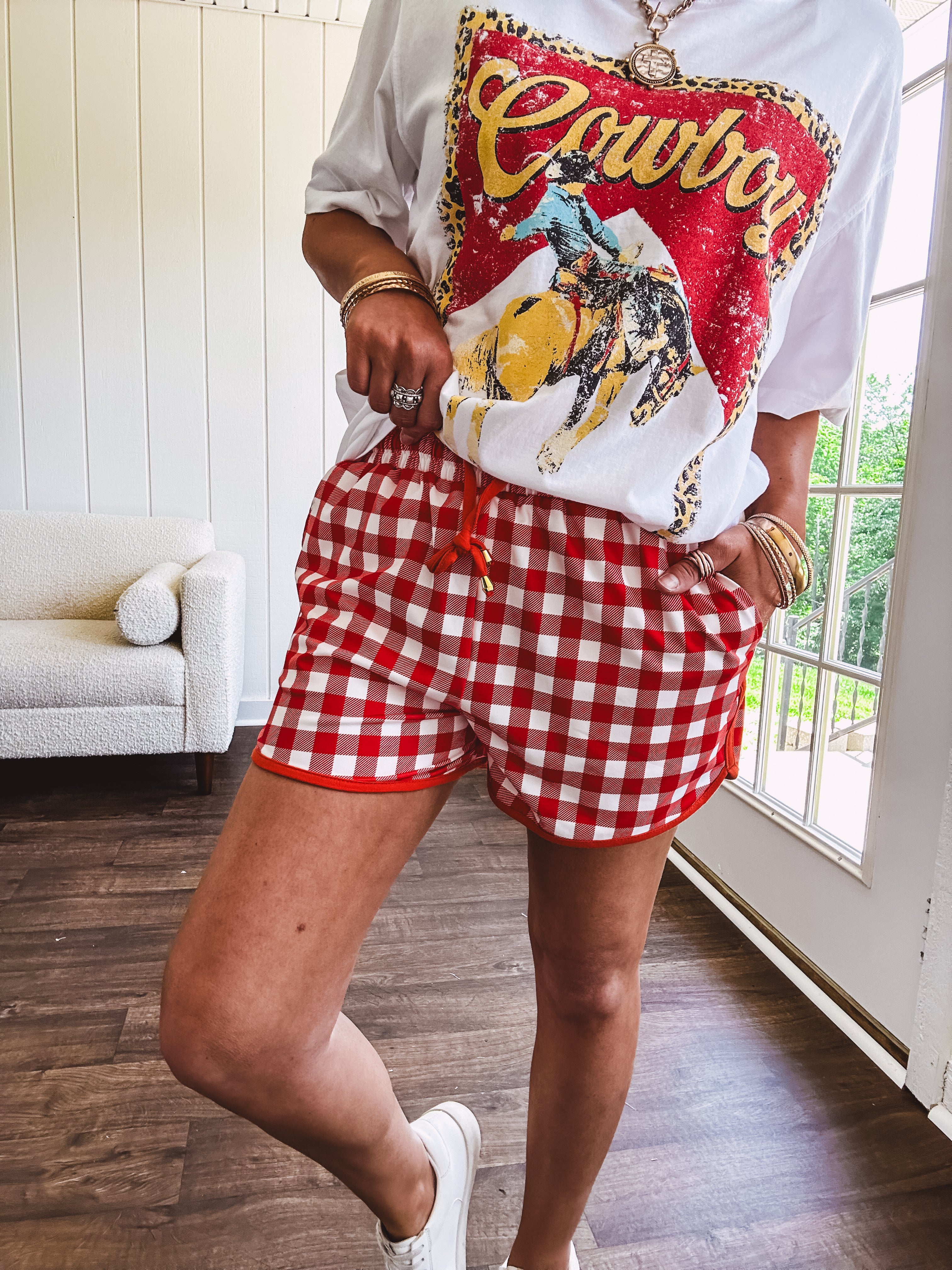 Thin, lightweight orange/red gingham athleisure shorts with elastic drawstring waist, pockets and matching trim.
