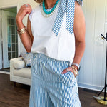 The lightweight cream tank features a playful blue and white striped bow at the shoulder and matching trim around the round neckline, finished with a hook and eye closure. Pair it with the coordinating wide-leg pants, complete with pockets and that same breezy stripe detail at the waist.