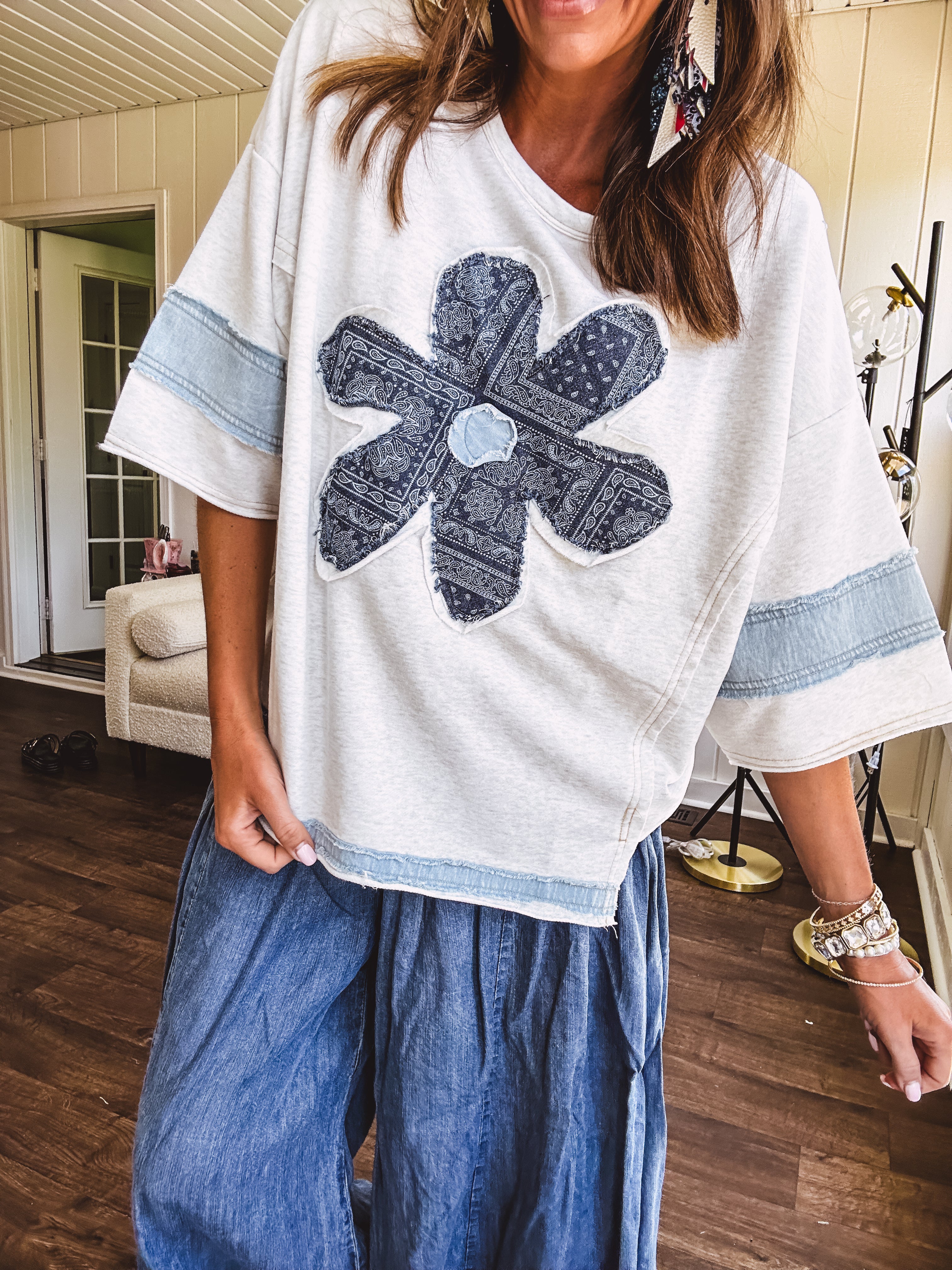 Soft, thin, lightweight 3/4 sleeve heather grey top with denim blue floral patchwork on the front and light blue patchwork on the sleeves and trim.