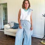 The lightweight cream tank features a playful blue and white striped bow at the shoulder and matching trim around the round neckline, finished with a hook and eye closure. Pair it with the coordinating wide-leg pants, complete with pockets and that same breezy stripe detail at the waist.