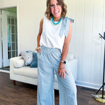 The lightweight cream tank features a playful blue and white striped bow at the shoulder and matching trim around the round neckline, finished with a hook and eye closure. Pair it with the coordinating wide-leg pants, complete with pockets and that same breezy stripe detail at the waist.