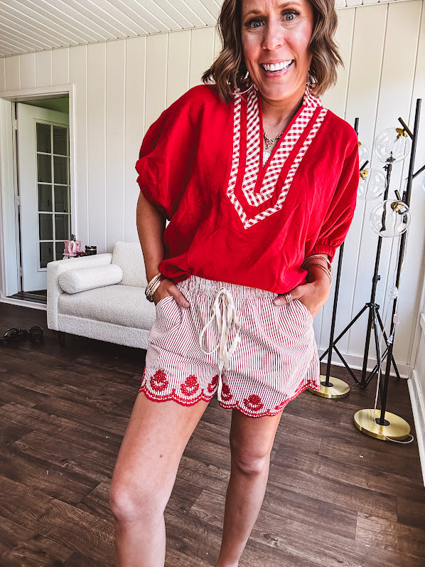 Cotton blend red and white striped shorts with elastic drawstring waist and embroidered red scalloped hem and pockets.