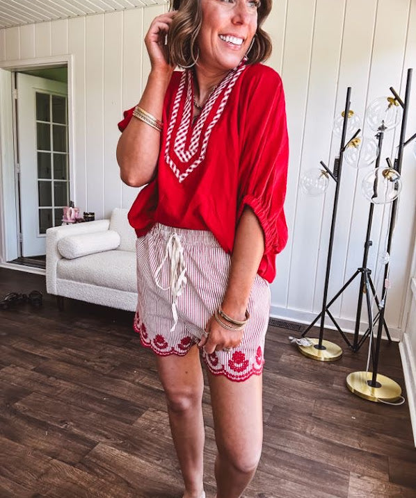 Cotton blend red and white striped shorts with elastic drawstring waist and embroidered red scalloped hem and pockets.