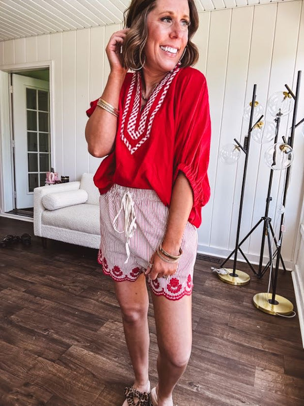 Cotton blend red and white striped shorts with elastic drawstring waist and embroidered red scalloped hem and pockets.