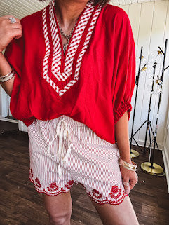Cotton blend red and white striped shorts with elastic drawstring waist and embroidered red scalloped hem and pockets.