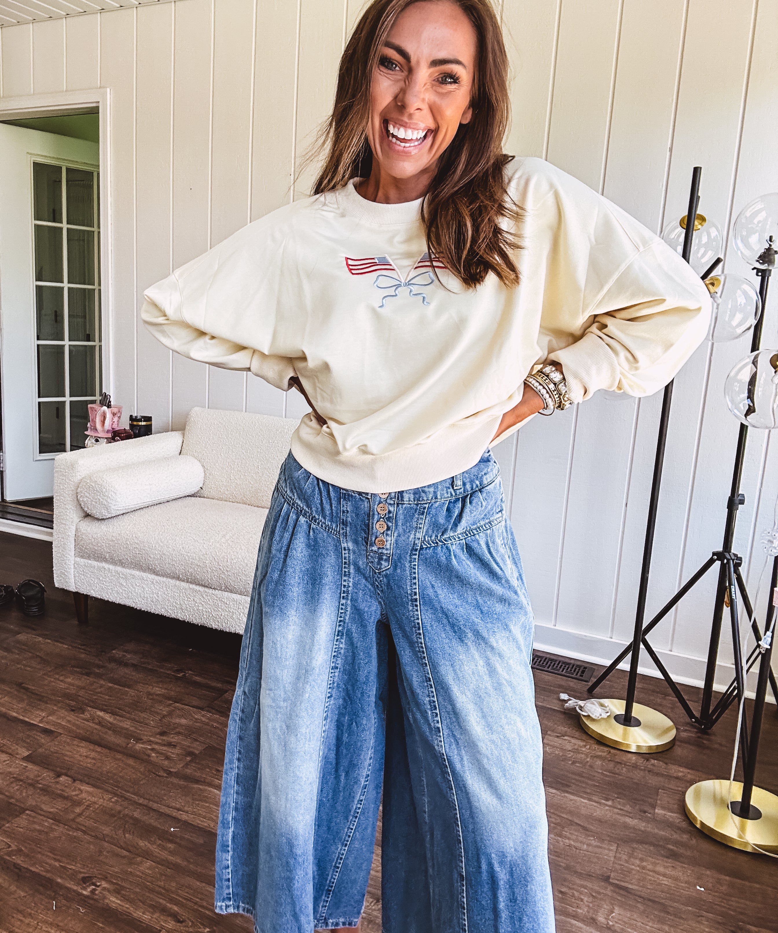 Cropped creamy light weight crew pullover with long sleeves and American flag embroidery with a light blue bow on the front.
