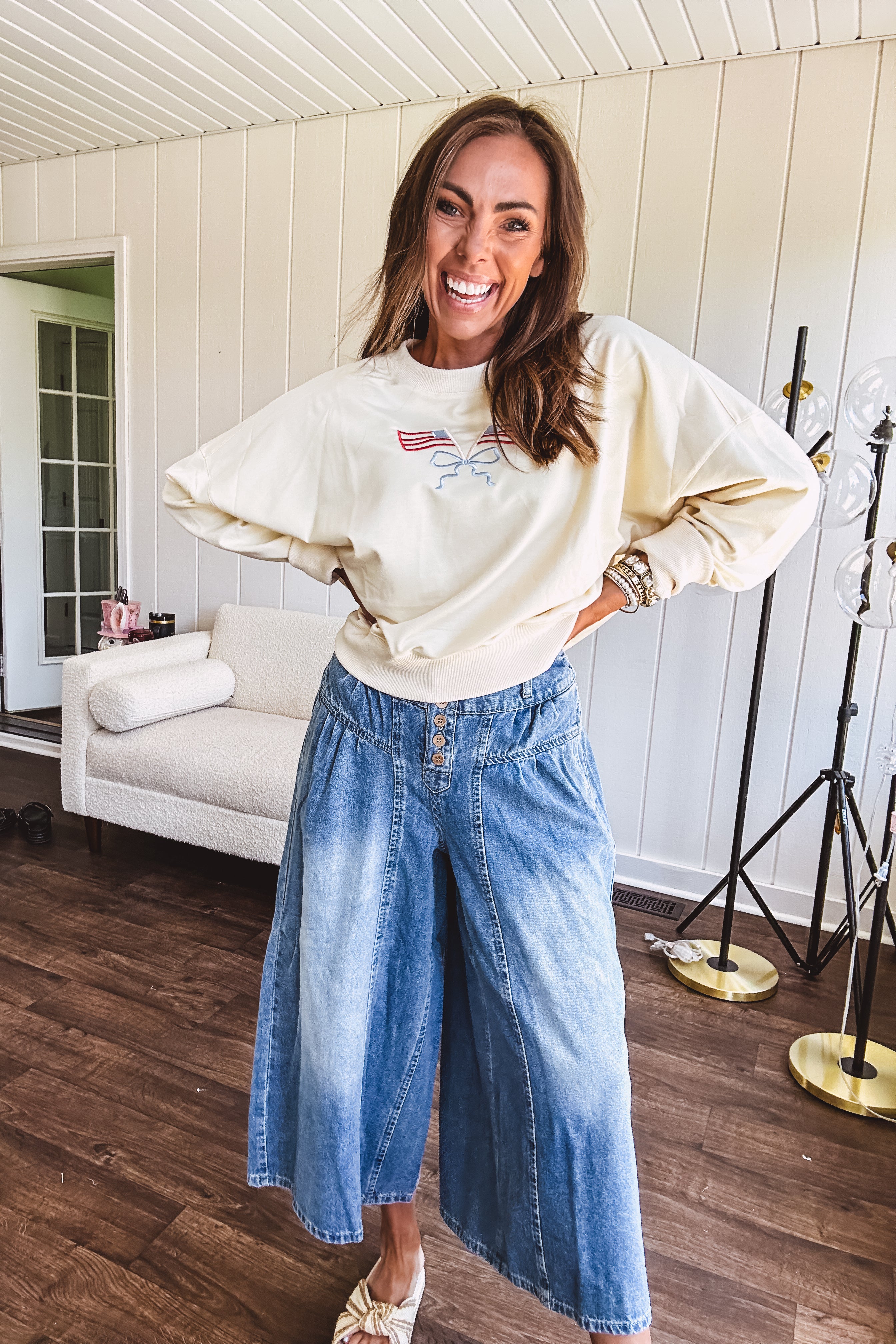Cropped creamy light weight crew pullover with long sleeves and American flag embroidery with a light blue bow on the front.