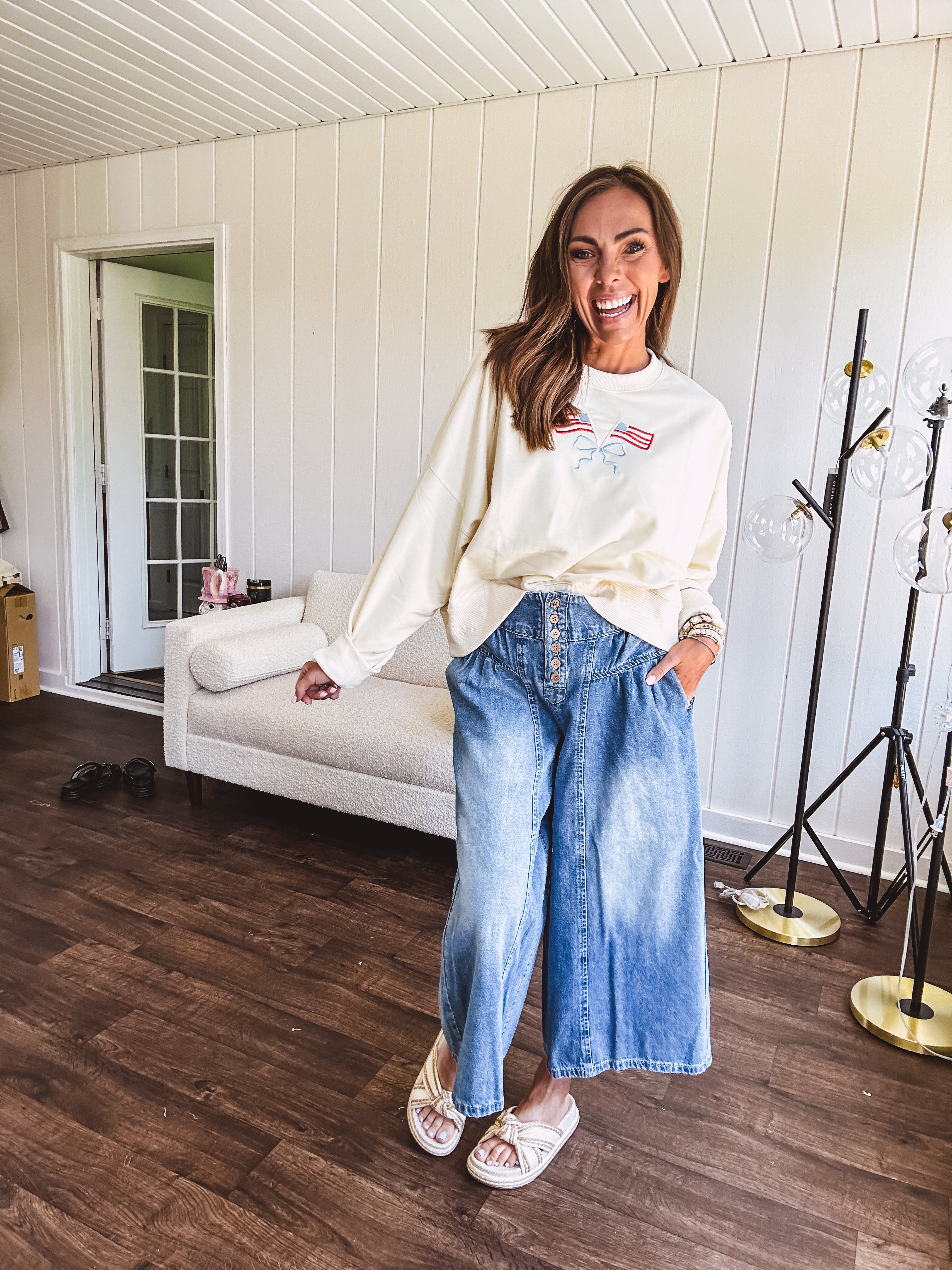 Cropped creamy light weight crew pullover with long sleeves and American flag embroidery with a light blue bow on the front.