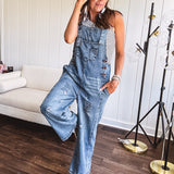 Loose fit medium wash denim overalls with adjustable button straps and sides and distressing throughout.