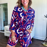 Soft, lightweight set featuring a 3/4 tab sleeve top with button down front and collar with matching elastic waist shorts with front pleats and pockets as well as lining in a bold navy, orange and white modern print.