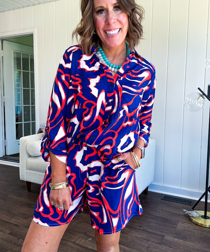 Soft, lightweight set featuring a 3/4 tab sleeve top with button down front and collar with matching elastic waist shorts with front pleats and pockets as well as lining in a bold navy, orange and white modern print.
