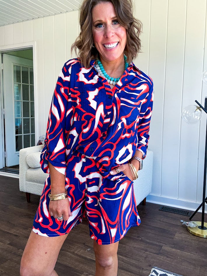 Soft, lightweight set featuring a 3/4 tab sleeve top with button down front and collar with matching elastic waist shorts with front pleats and pockets as well as lining in a bold navy, orange and white modern print.