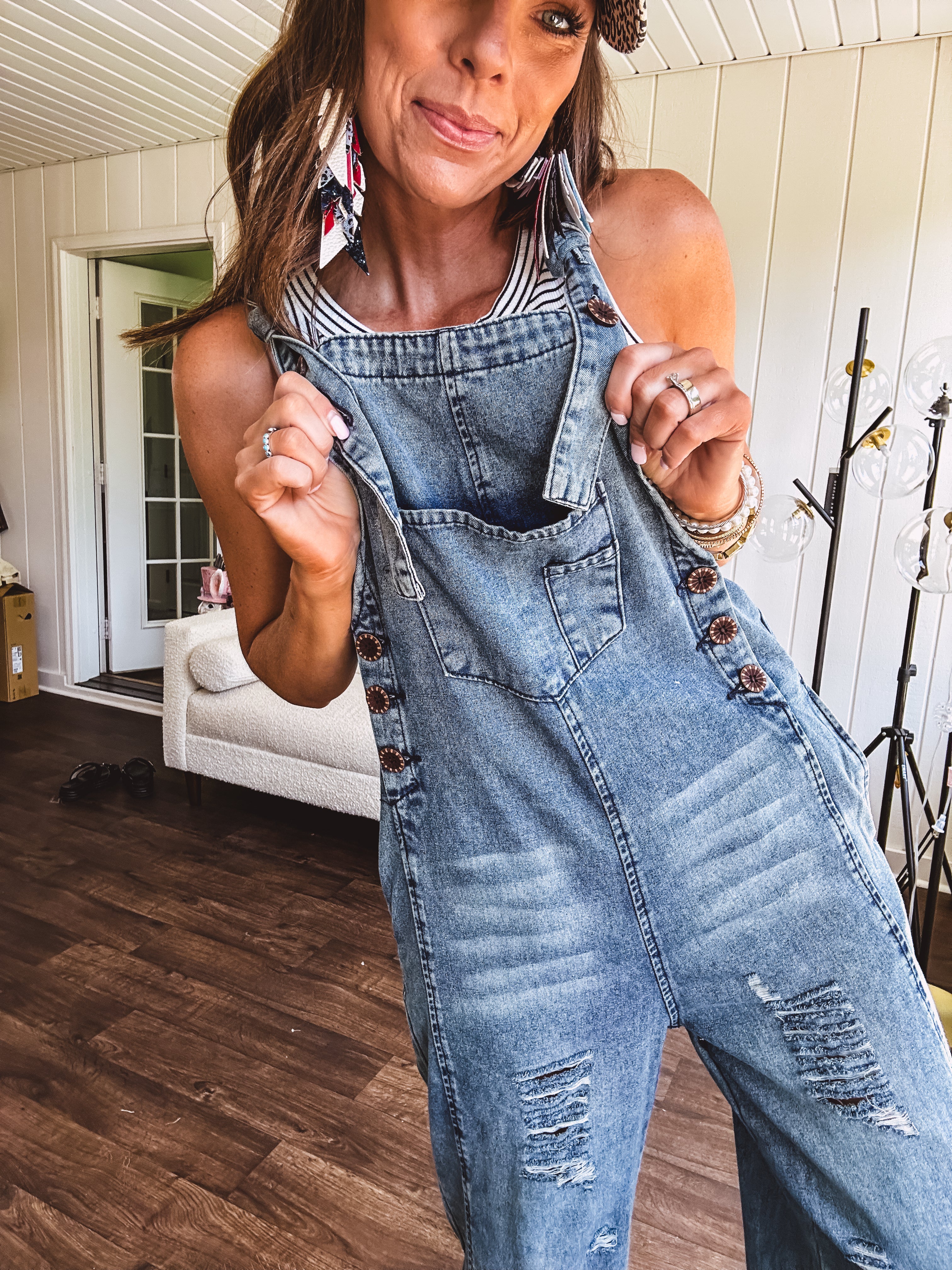 Loose fit medium wash denim overalls with adjustable button straps and sides and distressing throughout.