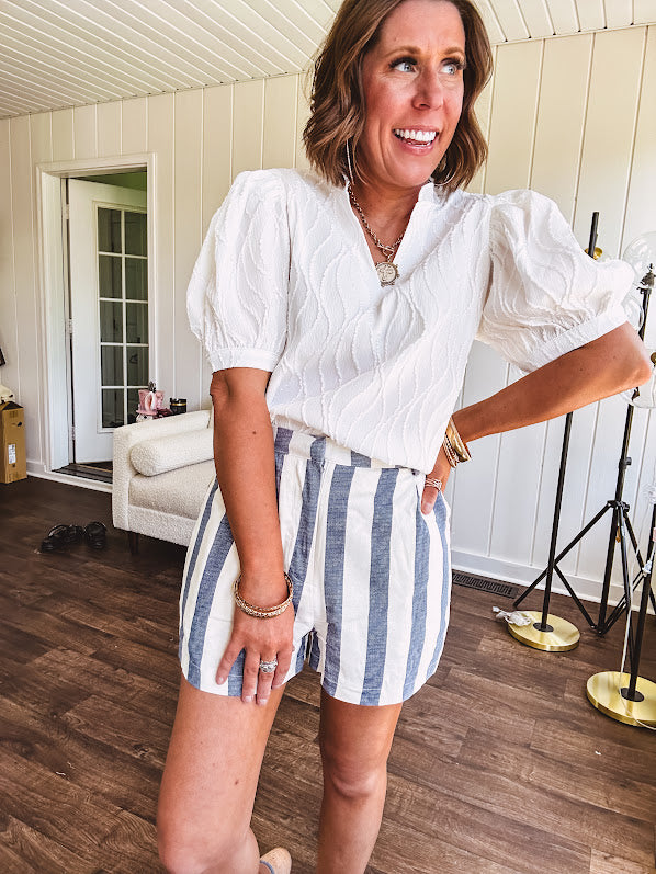 White puff sleeve blouse with wavy textured design, mock neck collar and V neck.