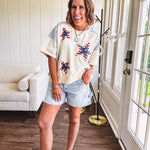 Cream short sleeved terry-like top with light blue inserts on shoulders and down sides with red and white stripe and denim blue star patches on the front.