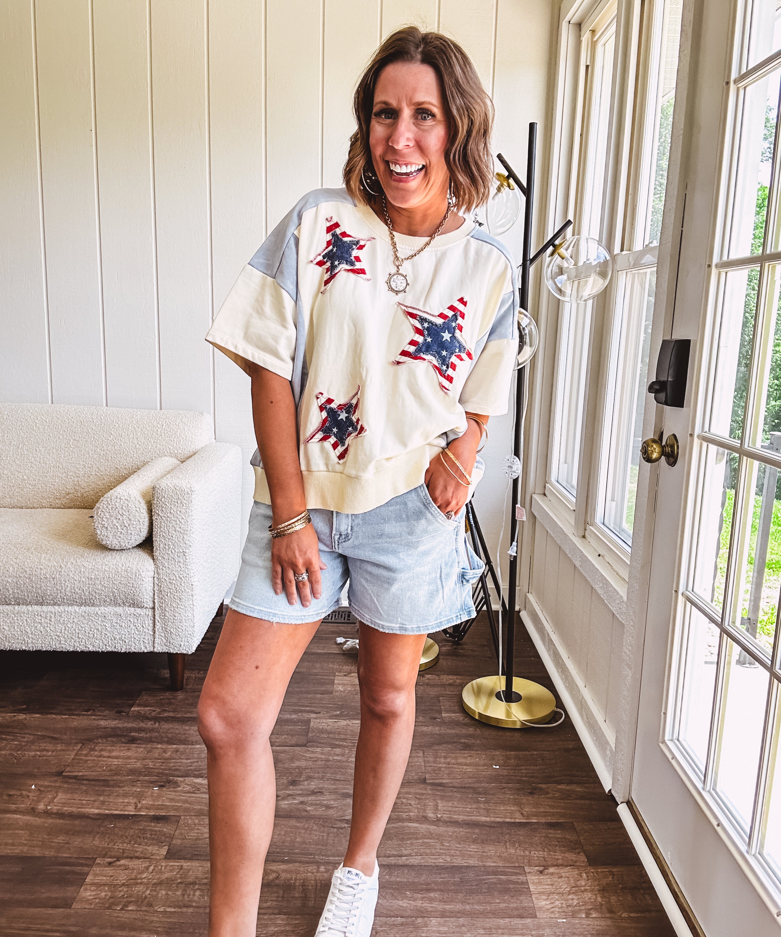 Cream short sleeved terry-like top with light blue inserts on shoulders and down sides with red and white stripe and denim blue star patches on the front.