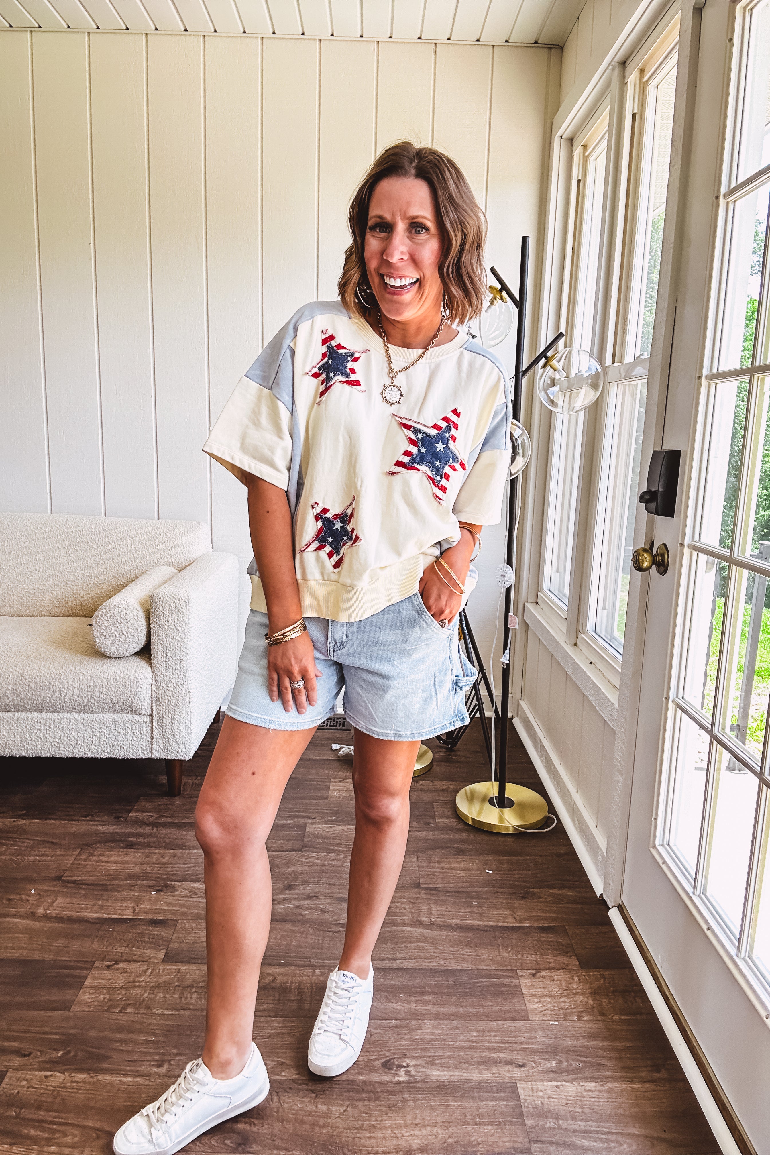 Cream short sleeved terry-like top with light blue inserts on shoulders and down sides with red and white stripe and denim blue star patches on the front.