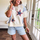 Cream short sleeved terry-like top with light blue inserts on shoulders and down sides with red and white stripe and denim blue star patches on the front.