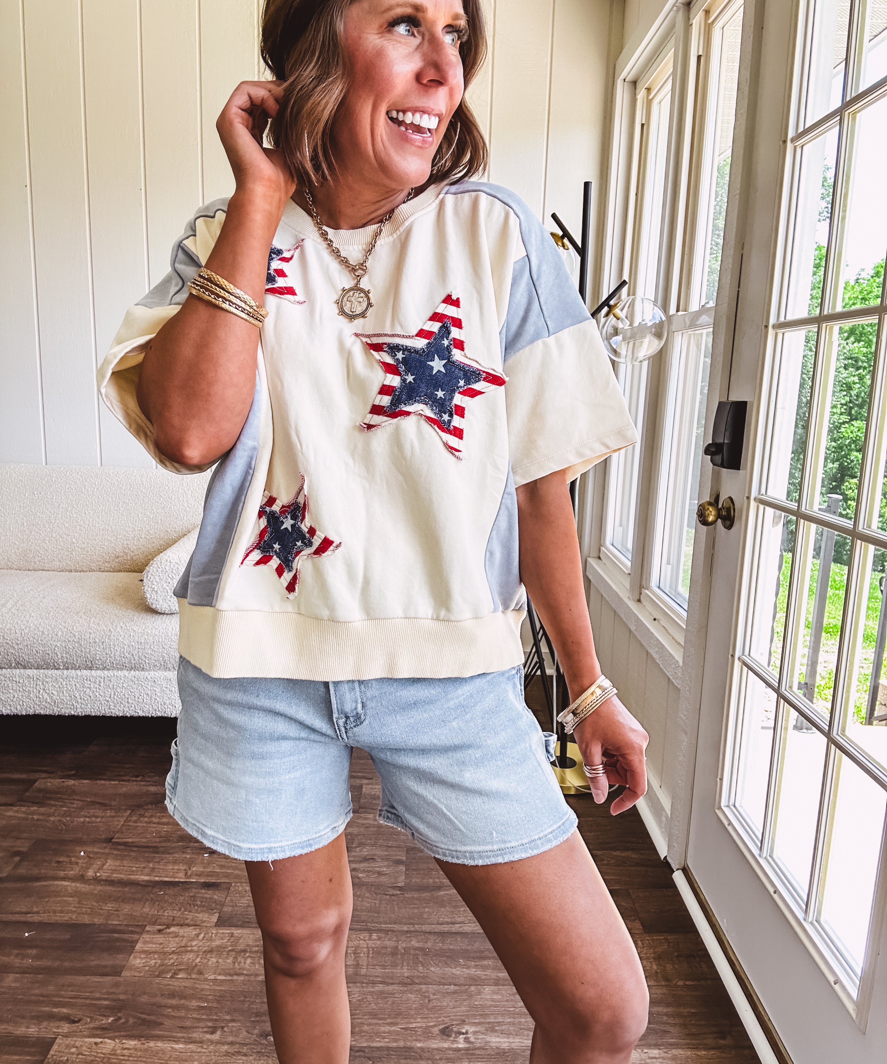 Cream short sleeved terry-like top with light blue inserts on shoulders and down sides with red and white stripe and denim blue star patches on the front.
