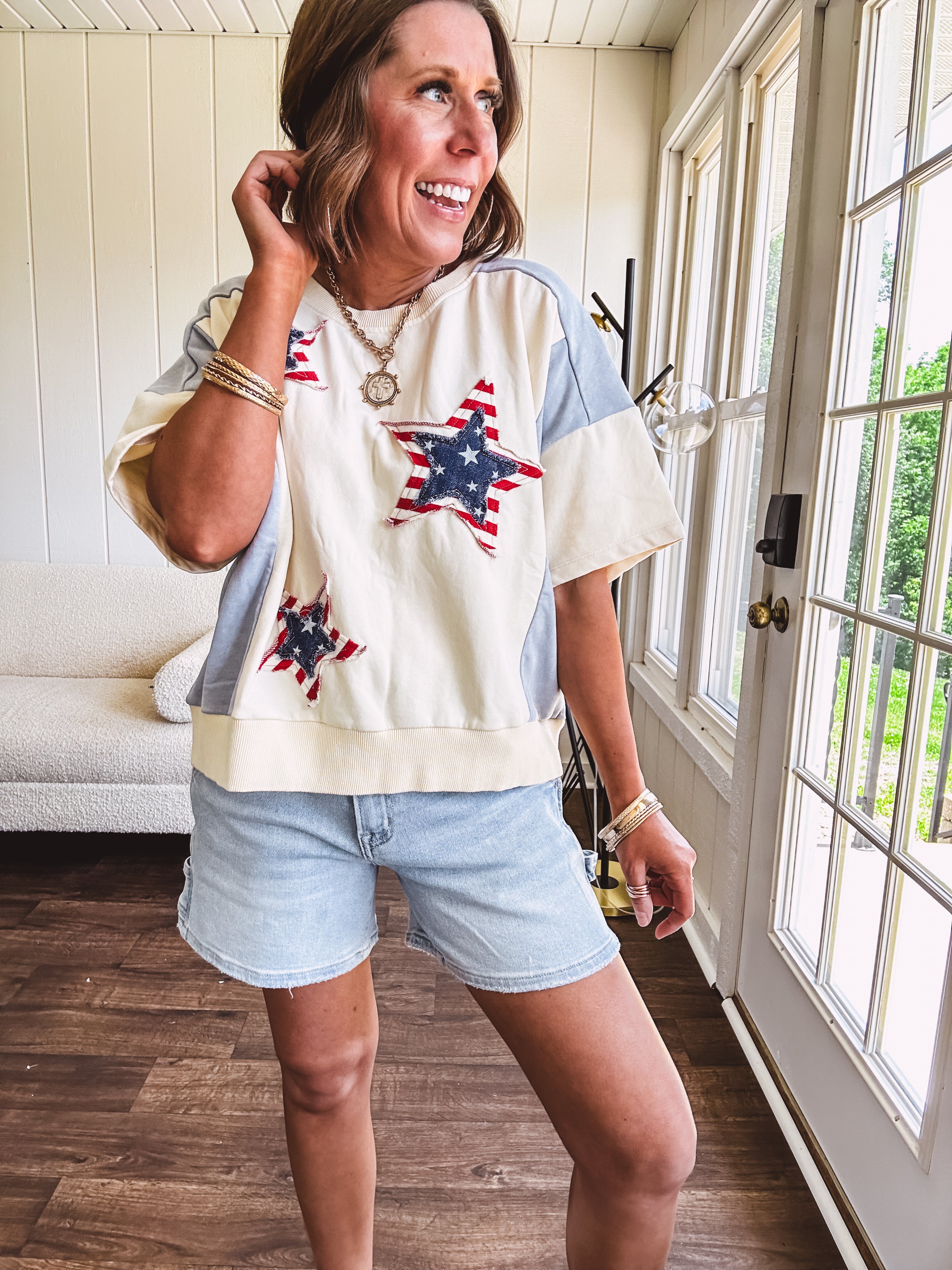 Cream short sleeved terry-like top with light blue inserts on shoulders and down sides with red and white stripe and denim blue star patches on the front.