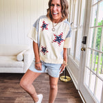 Cream short sleeved terry-like top with light blue inserts on shoulders and down sides with red and white stripe and denim blue star patches on the front.