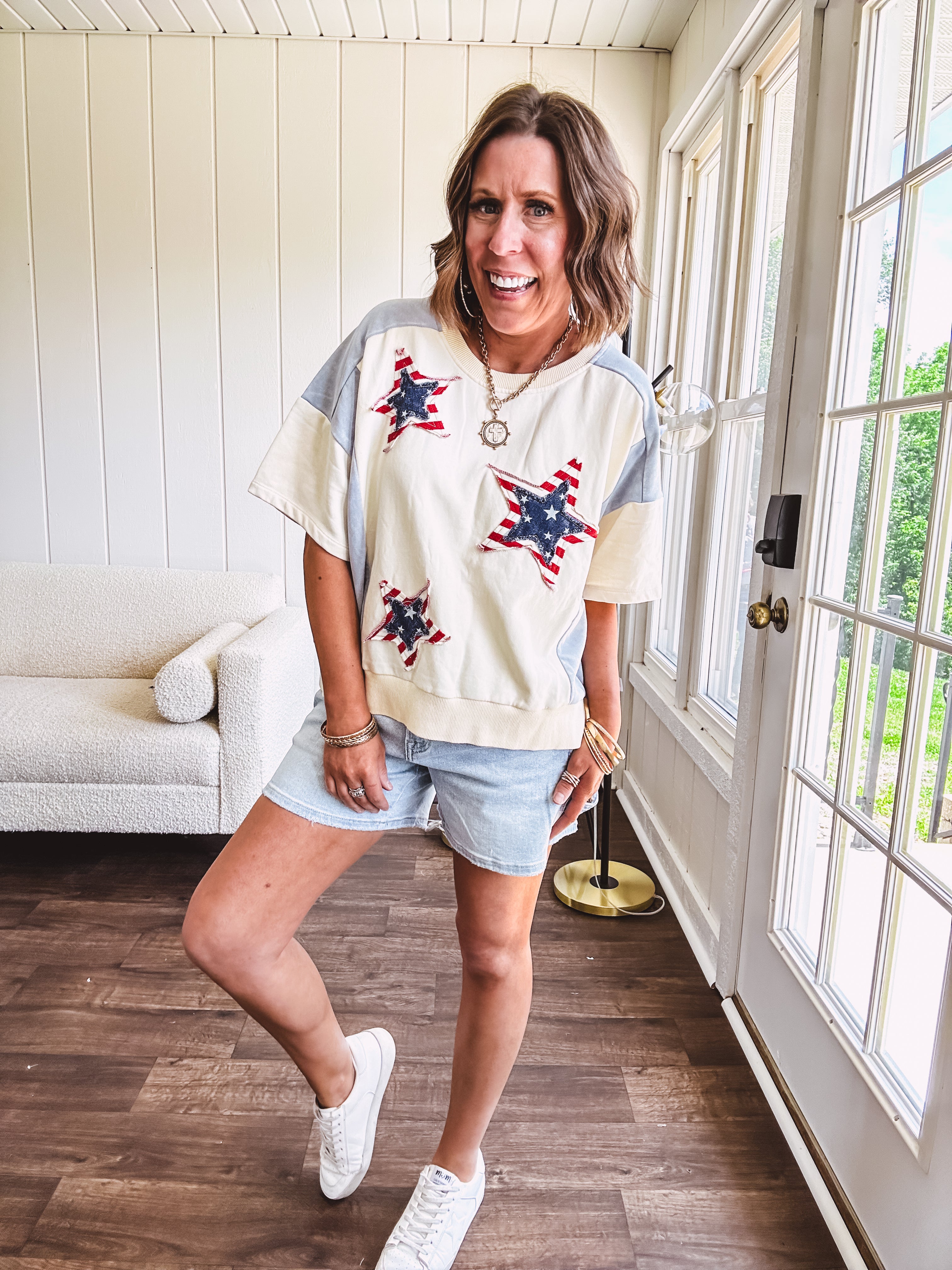 Cream short sleeved terry-like top with light blue inserts on shoulders and down sides with red and white stripe and denim blue star patches on the front.