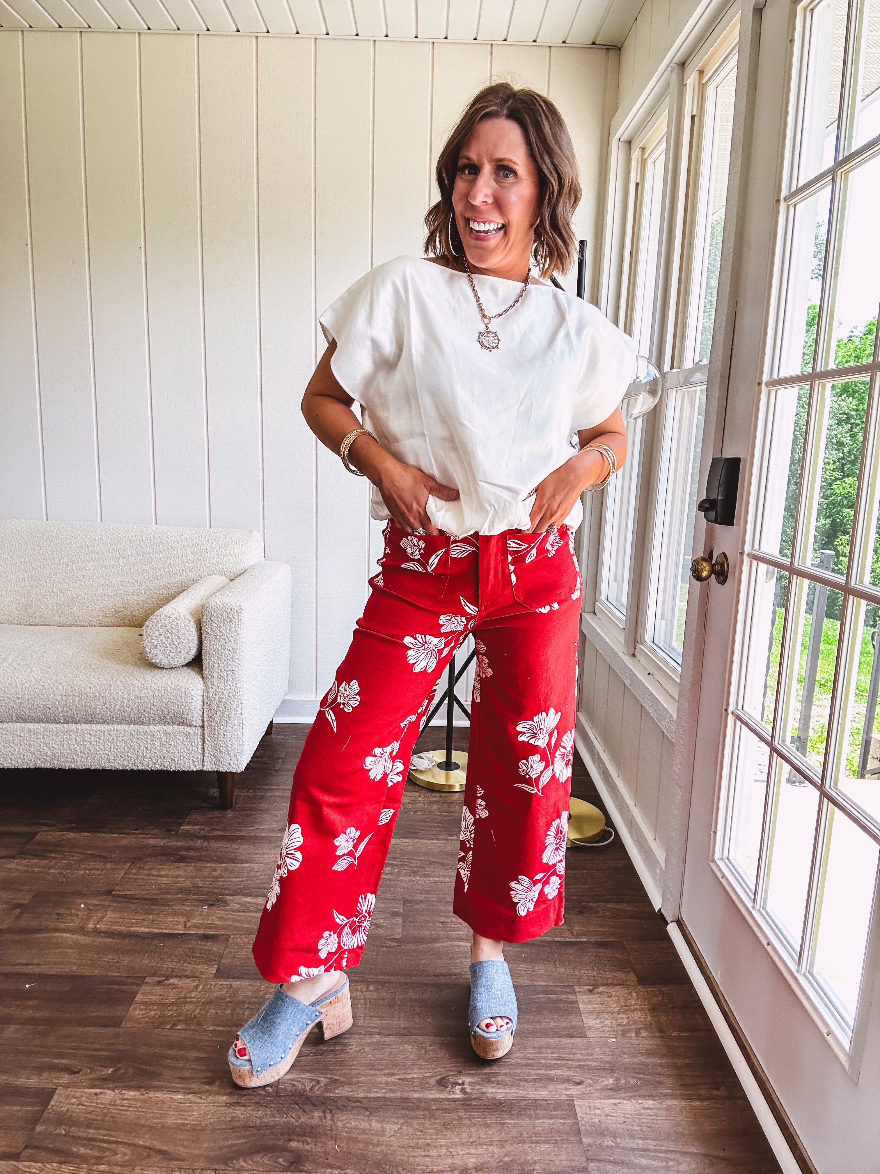 Wide leg cropped red pants with white florals throughout, button and zipper closure, wide cuffs and square front pockets. Minimal stretch