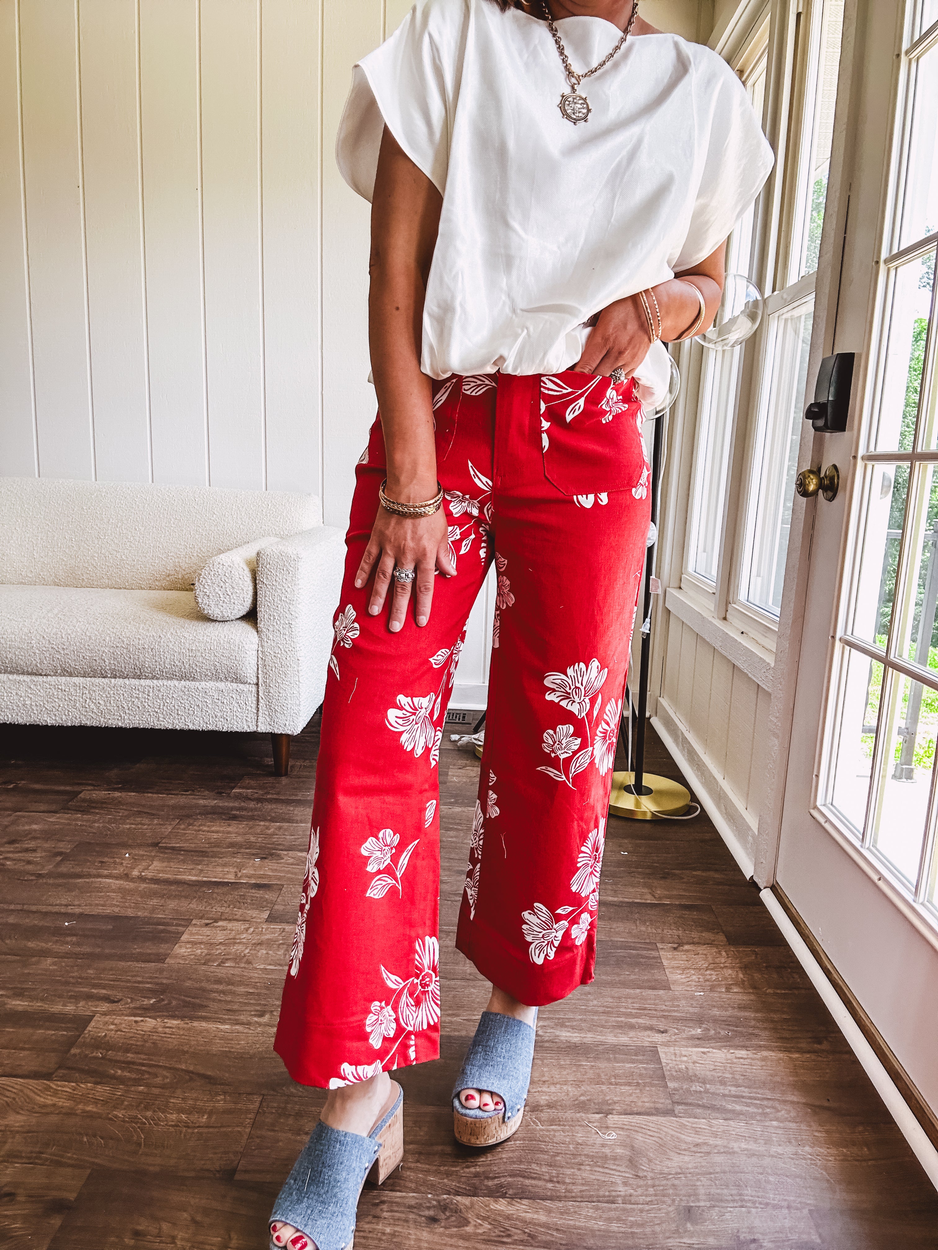 Wide leg cropped red pants with white florals throughout, button and zipper closure, wide cuffs and square front pockets. Minimal stretch