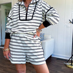 Lightweight cream and black striped set with 1/4 zip and collar top with black trim at the yoke and cuffs on the long sleeves and matching elastic waist shorts with pockets and black trim down the sides.