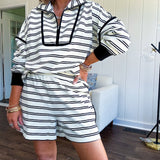 Lightweight cream and black striped set with 1/4 zip and collar top with black trim at the yoke and cuffs on the long sleeves and matching elastic waist shorts with pockets and black trim down the sides.