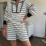 Lightweight cream and black striped set with 1/4 zip and collar top with black trim at the yoke and cuffs on the long sleeves and matching elastic waist shorts with pockets and black trim down the sides.