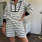 Lightweight cream and black striped set with 1/4 zip and collar top with black trim at the yoke and cuffs on the long sleeves and matching elastic waist shorts with pockets and black trim down the sides.