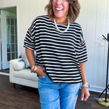 Soft, lightweight stretchy fabric in stripes including black and white, cream and white with contrasting trim at the round neck, hemline and sleeves. short sleeved and boxy cut.
