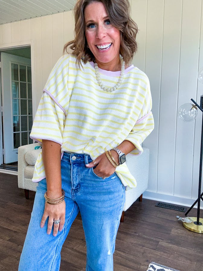 Soft, lightweight stretchy fabric in stripes including black and white, cream and white with contrasting trim at the round neck, hemline and sleeves. short sleeved and boxy cut.