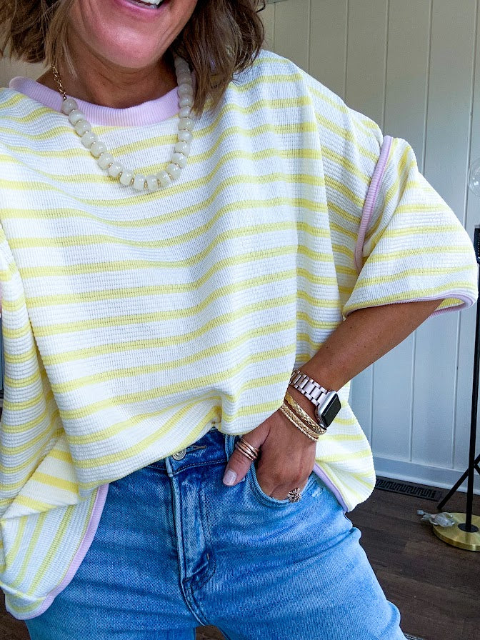 Soft, lightweight stretchy fabric in stripes including black and white, cream and white with contrasting trim at the round neck, hemline and sleeves. short sleeved and boxy cut.