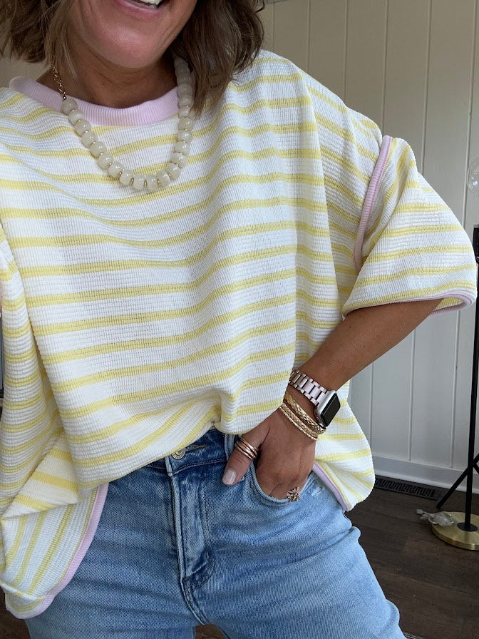 Soft, lightweight stretchy fabric in stripes including black and white, cream and white with contrasting trim at the round neck, hemline and sleeves. short sleeved and boxy cut.