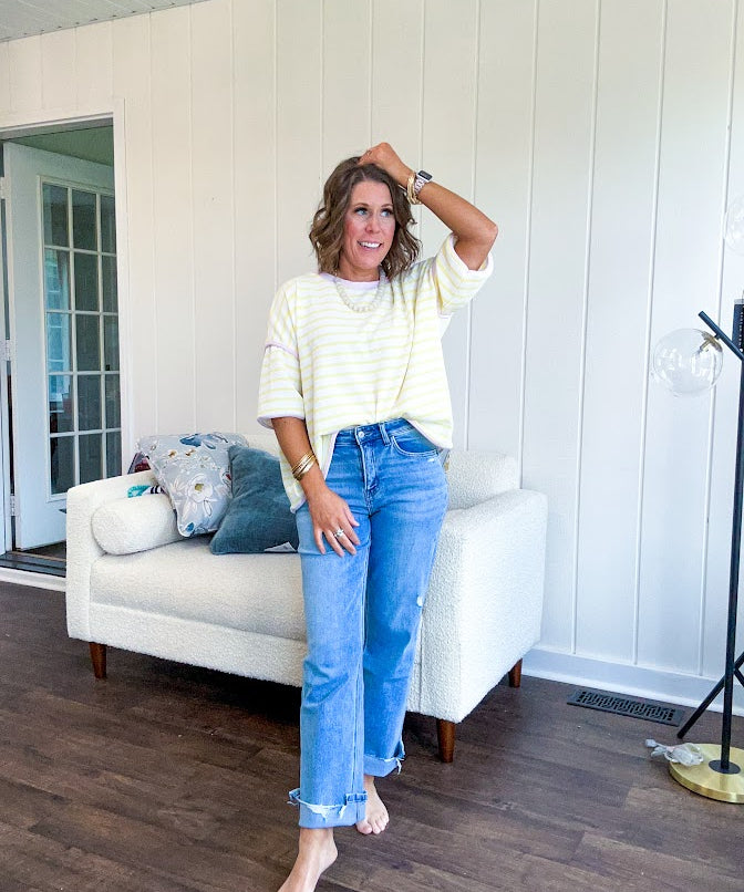 Light wash high rise denim with stretch, zipper button closure, minimal distressing and raw cutout at the hem with a straight leg design that is slim through the thighs.