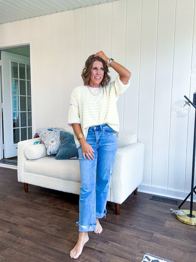 Light wash high rise denim with stretch, zipper button closure, minimal distressing and raw cutout at the hem with a straight leg design that is slim through the thighs.