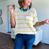 A boxy cream open weave knit that's equal parts playful and put-together. Sunshine-yellow stripes dance across the fabric while a bold teal collar and scalloped sleeve trim steal the show. The front pocket? Pure casual genius.