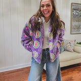 Long sleeved sherpa jacket in lavender with right ivory, green and pink florals, a detachable grey hoodie, gold zipper front and pockets.