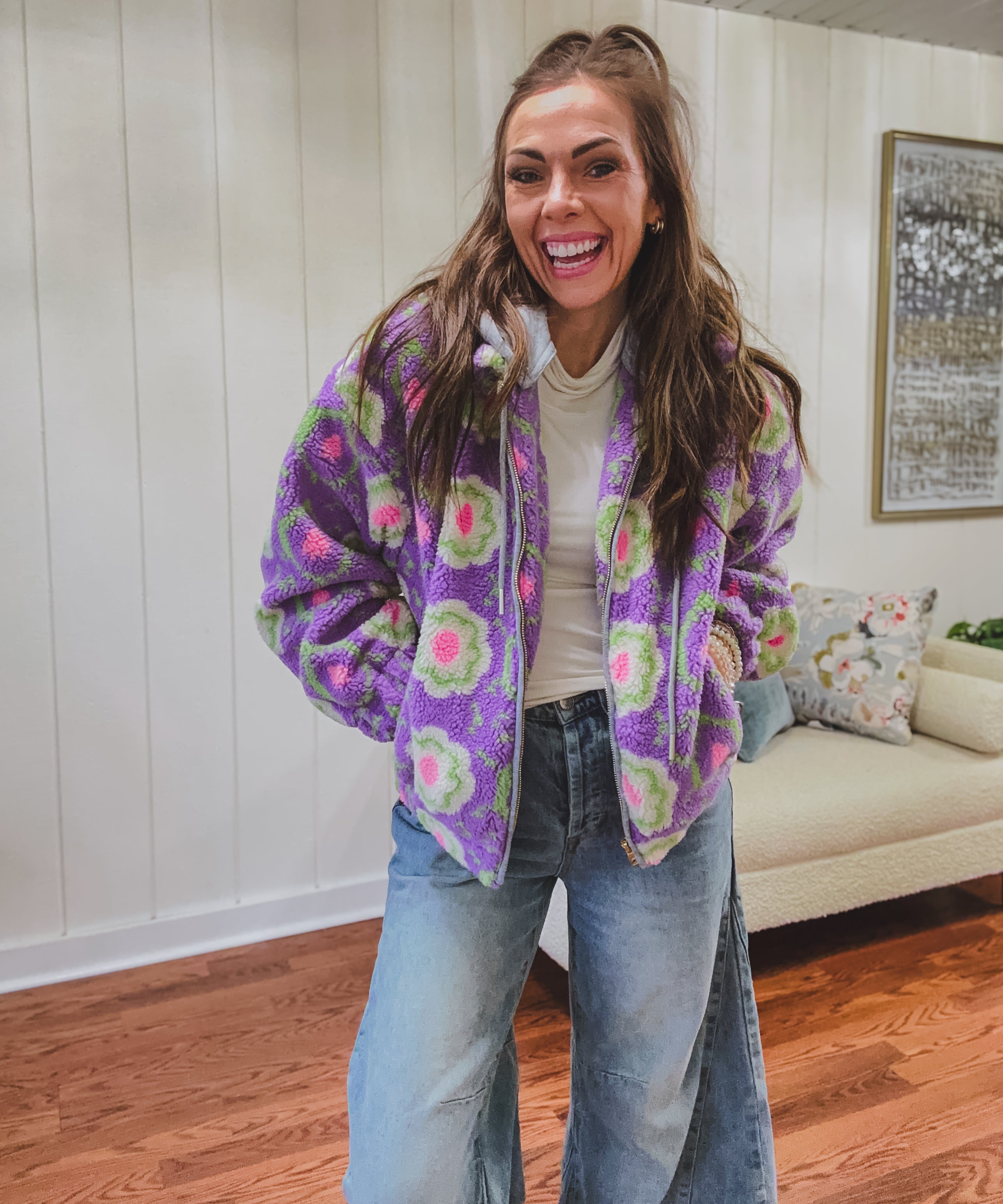Long sleeved sherpa jacket in lavender with right ivory, green and pink florals, a detachable grey hoodie, gold zipper front and pockets.