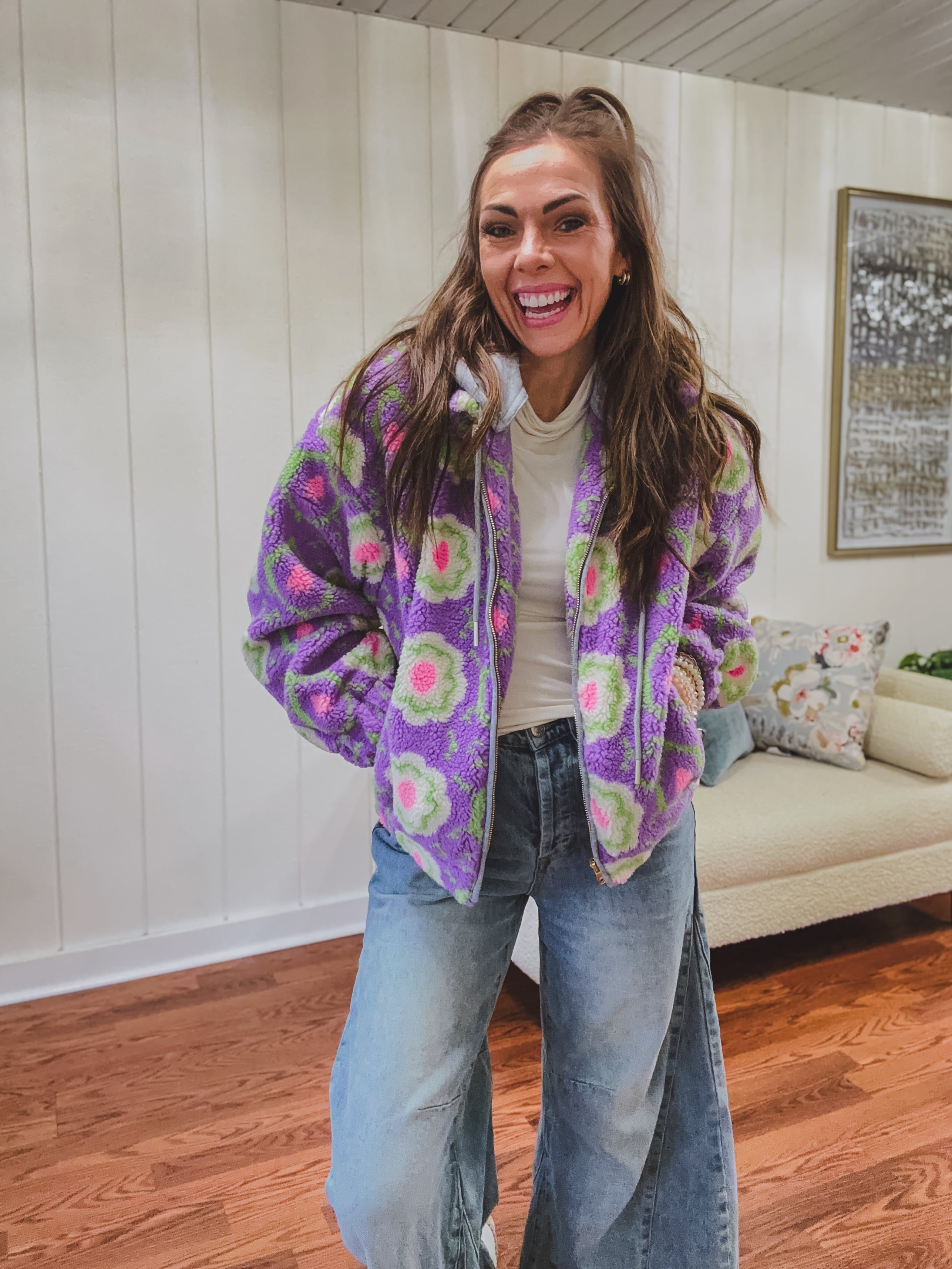 Long sleeved sherpa jacket in lavender with right ivory, green and pink florals, a detachable grey hoodie, gold zipper front and pockets.
