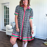 Black cotton mini dress with coral and green floral print, coral and green collar, placket, and hem with button down front and short sleeves. Has pockets.