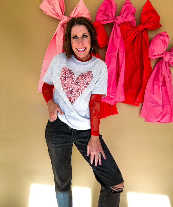 Light grey heathered tee with a pink and red heart made of bows on the front.
