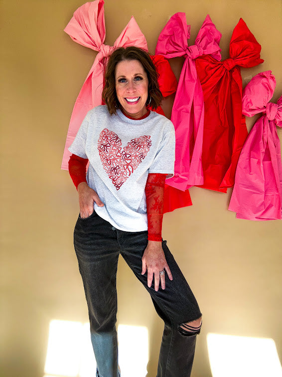 Light grey heathered tee with a pink and red heart made of bows on the front.