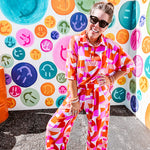 Thin, lightweight and stretchy set featuring fuchsia, orange, coral and ivory abstract print with 1/4 gold button front and collar on the short sleeved top and matching wide leg pants with elastic waist and pockets.