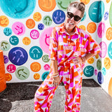 Thin, lightweight and stretchy set featuring fuchsia, orange, coral and ivory abstract print with 1/4 gold button front and collar on the short sleeved top and matching wide leg pants with elastic waist and pockets.