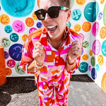 Thin, lightweight and stretchy set featuring fuchsia, orange, coral and ivory abstract print with 1/4 gold button front and collar on the short sleeved top and matching wide leg pants with elastic waist and pockets.