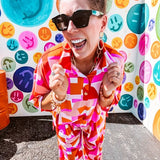 Thin, lightweight and stretchy set featuring fuchsia, orange, coral and ivory abstract print with 1/4 gold button front and collar on the short sleeved top and matching wide leg pants with elastic waist and pockets.