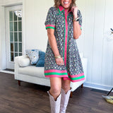 Black cotton mini dress with coral and green floral print, coral and green collar, placket, and hem with button down front and short sleeves. Has pockets.